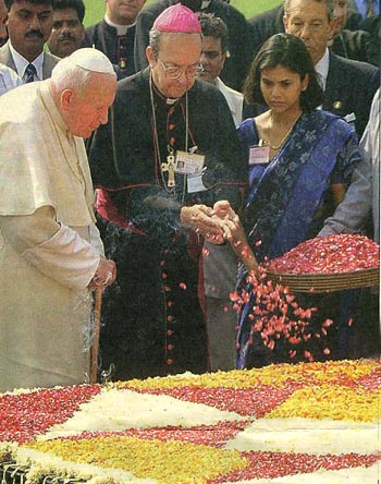 John Paul II and a cardinal strew flower petals on Gandhi's tomb